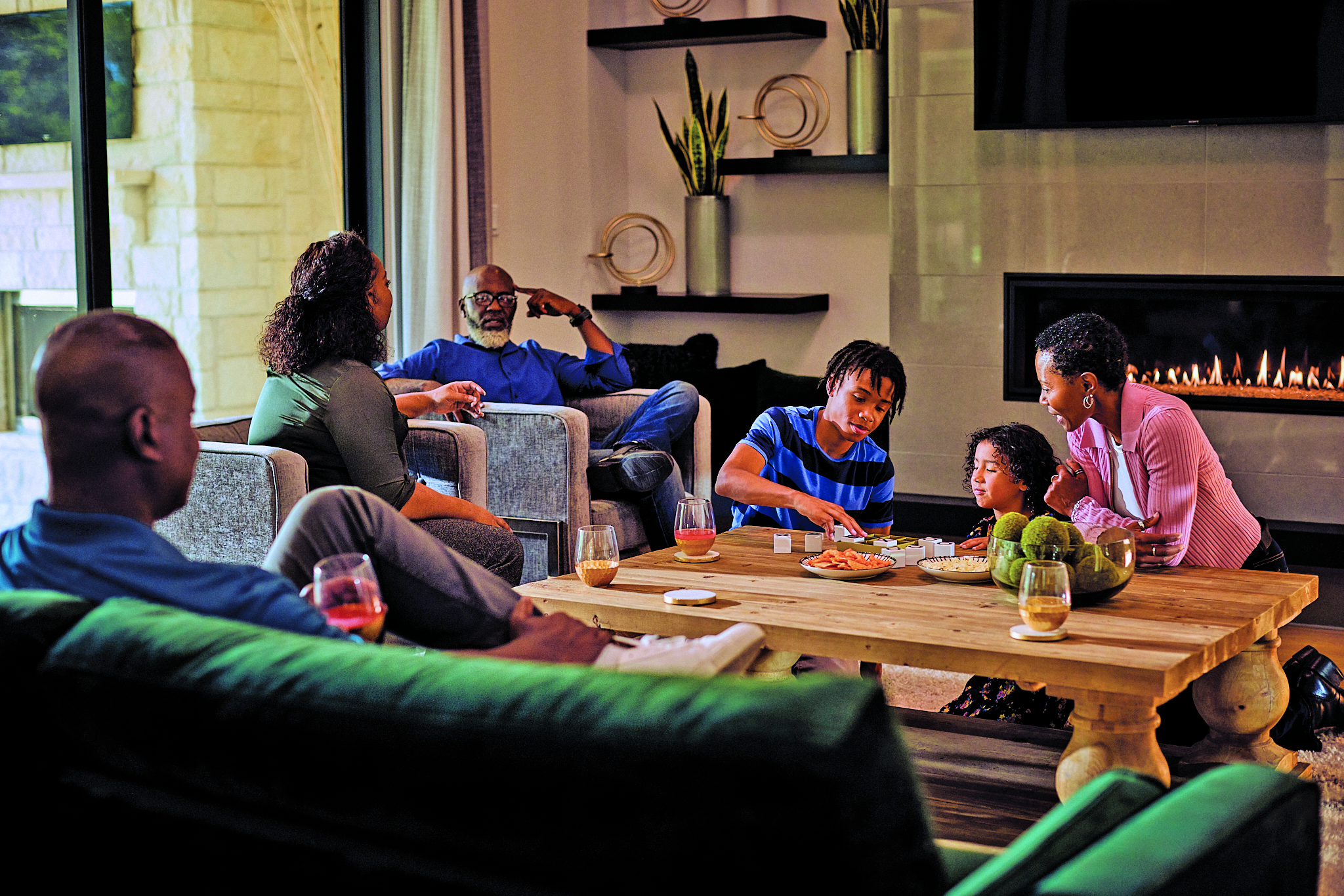 Family sitting around gas fireplace playing games.